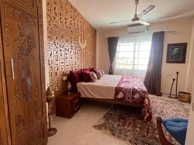 a bedroom with a bed and a wall with a mural at Amenti House - Private Villa & Retreat Center in Luxor