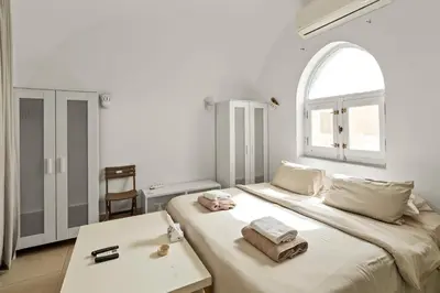 a white bedroom with a bed and an arch window at The Downtown Getaway Studio in Hurghada