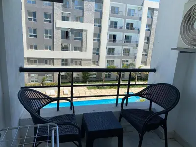 a balcony with two chairs and a view of a pool at Fanader bay sea view apartment in Hurghada