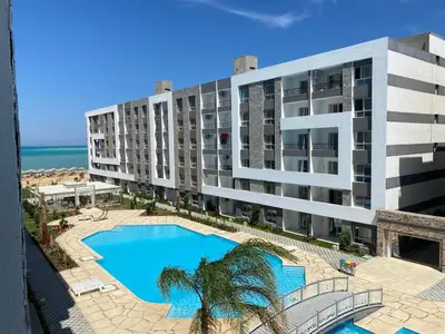 an aerial view of a building with a swimming pool and the beach at Fanader bay sea view apartment in Hurghada
