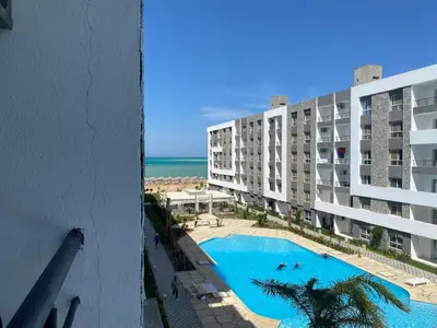 a view of a building with a swimming pool and the ocean at Fanader bay sea view apartment in Hurghada
