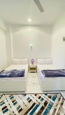 two beds in a white room with a table at Star - private apartments in Luxor