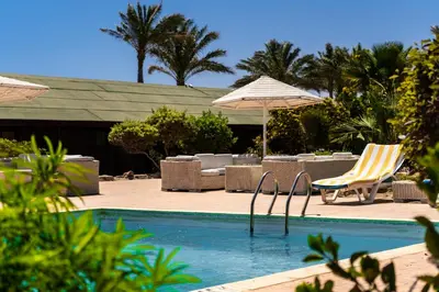 a swimming pool with chairs and umbrellas next to a resort at Abu Dabbab Lodge in Abu Dabab