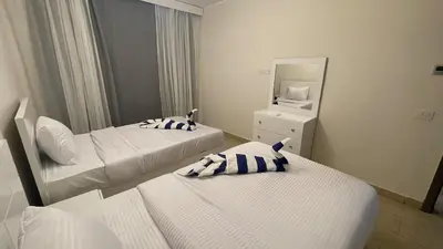 a hotel room with two beds and a mirror at Dani Apartment at Aldau Heights in Hurghada