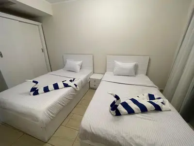 two beds with blue and white pillows in a room at Dani Apartment at Aldau Heights in Hurghada