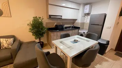 a small living room with a table and a kitchen at Dani Apartment at Aldau Heights in Hurghada