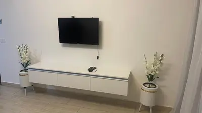 a white desk with a tv on a wall at Dani Apartment at Aldau Heights in Hurghada