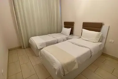 two beds in a hotel room with white sheets and pillows at Family apartment Aldau Heights in Hurghada