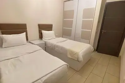 two beds in a small room with a door at Family apartment Aldau Heights in Hurghada