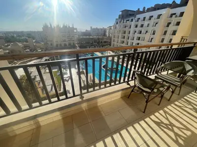 a balcony with two chairs and a view of a pool at Galaxy Aldau heights 2 bedrooms in Hurghada