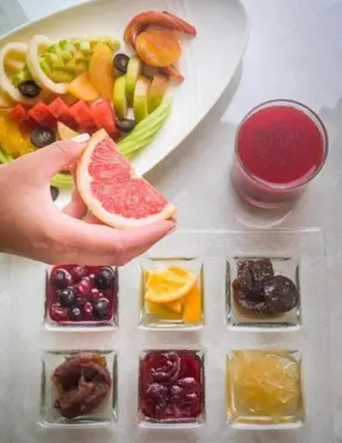 a person holding a slice of fruit next to a plate of food at Juliana Beach Resort AG01 in Hurghada