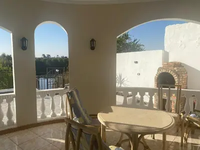 a dining room with a table and two windows at villa on Nile in Luxor