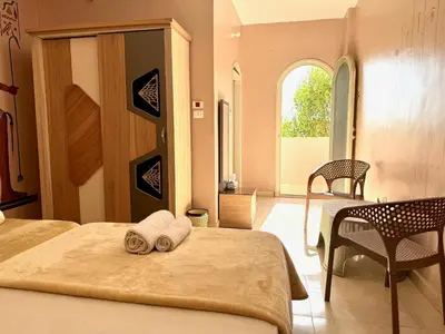 a bedroom with two beds and a table and a window at MAGIC GUEST HOUSE - Δ Relax Pur Δ 15 MiN TO ASWAN in Aswan