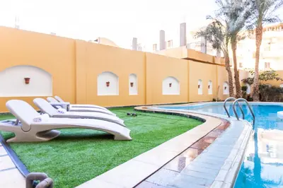 a resort with a swimming pool with lounge chairs next to a building at Lazur Pool Apartment's - El Kawsar, Hurghada - Egypt in Hurghada