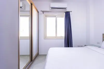 a bedroom with a mirror and a bed and a window at Lazur Pool Apartment's - El Kawsar, Hurghada - Egypt in Hurghada