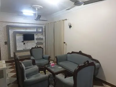 a living room with chairs and a table and a tv at El Quarn Apartment in ‘Ezbet Abu Ḥabashi