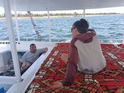 two men sitting on the back of a boat at Nuba Tod Sailling boat in Aswan