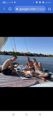 a group of men sitting on a dock on the water at Nuba Tod Sailling boat in Aswan