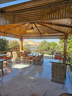 a wooden patio with tables and chairs and a view at King Mina Nubian House in Aswan