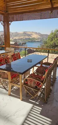 a table and chairs on a patio with a view of a river at King Mina Nubian House in Aswan