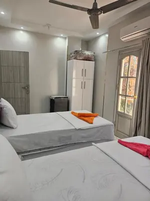 two beds in a room with a white refrigerator at King Mina Nubian House in Aswan
