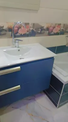 a bathroom with a white sink and a blue cabinet at اهلا بيكم في بيتنا in Jazīrat al ‘Awwāmīyah