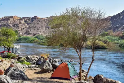 a tent on the rocks next to a river at ASSINGAR camp in Jazīrat Suhayl