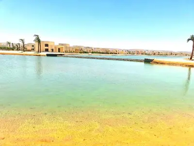 a large body of water with palm trees and buildings at شيدوان الجونة in El Gouna