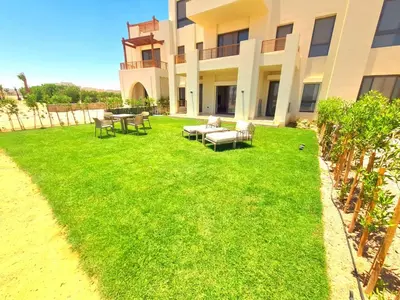 a lawn in front of a building with tables and chairs at شيدوان الجونة in El Gouna