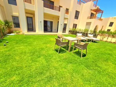 a lawn with tables and chairs in front of a building at شيدوان الجونة in El Gouna