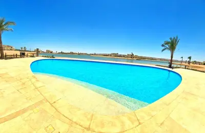a swimming pool with blue water and palm trees at شيدوان الجونة in El Gouna
