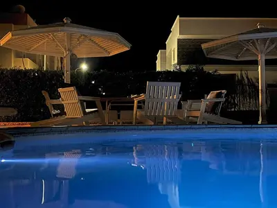a swimming pool with chairs and umbrellas at night at Hurghada-Magawish Studio 1 in Hurghada