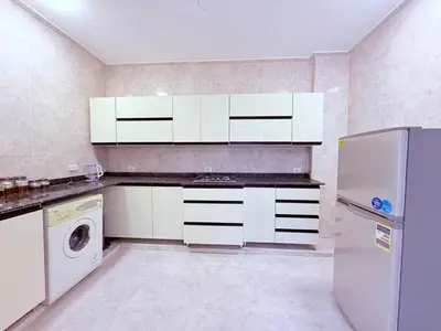 a kitchen with white cabinets and a washer and dryer at Sheherazade Guesthouse in Luxor