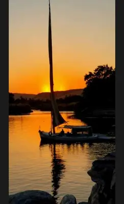 a sail boat on the water at sunset at sunset guest house in Aswan