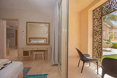 a room with a mirror and a bed and a chair at Ollystays Mangroovy 1 BR Beach and Pool Free access in Hurghada