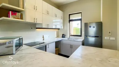 a kitchen with white cabinets and a stainless steel refrigerator at Ollystays 4BR Townhouse Shared Pool El Gouna in Hurghada