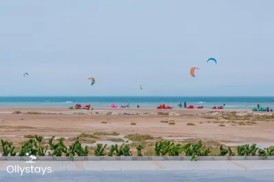 people on the beach with kites flying in the sky at Ollystays Mangroovy 3BR Beach and Pool Free access in Hurghada