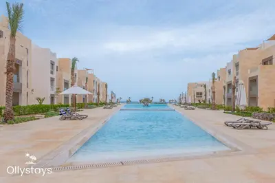 a swimming pool in a resort with palm trees and buildings at Ollystays Mangroovy Seaview 2BR Beach and Pool Free access in Hurghada