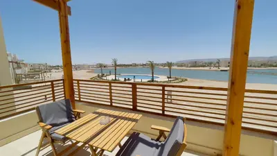 a balcony with a table and chairs and a swimming pool at Ollystays Shedwan 1BR Pool & lagoon access in Hurghada