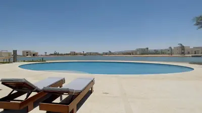 a swimming pool with two lounge chairs in front of it at Ollystays Shedwan 1BR Pool & lagoon access in Hurghada