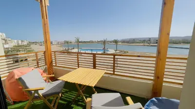a balcony with a table and chairs and a swimming pool at Ollystays Shedwan 1BR Pool & lagoon access in Hurghada