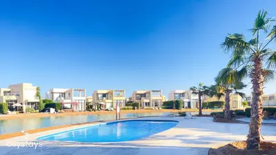 a swimming pool with palm trees in a resort at Ollystays Tawila 2BR Apt Shared pool El Gouna in Hurghada