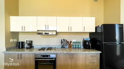 a kitchen with white cabinets and a black refrigerator at Ollystays Tawila 2BR Apt Shared pool El Gouna in Hurghada