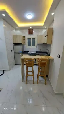 a kitchen with a wooden table and two chairs at الغردقه in Hurghada