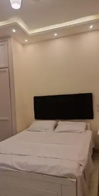 a bedroom with a white bed with a black headboard at منتجع اباظة السياحى in Hurghada