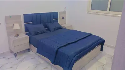 a bedroom with a blue bed and a night stand at اهلا بيكم في بيتنا in Jazīrat al ‘Awwāmīyah