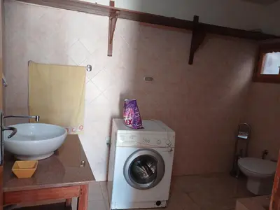 a bathroom with a washing machine and a sink at Habu view in Al Karnak