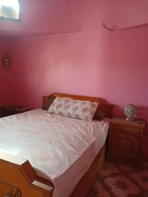 a bedroom with a bed and a pink wall at Habu view in Al Karnak