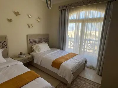 a bedroom with two beds and a large window at Your Red Sea Hideaway Apartment in Coraya Bay