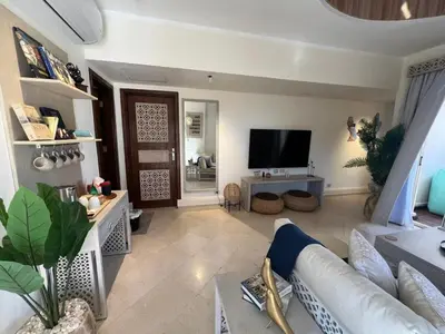 a living room with a couch and a tv at Your Red Sea Hideaway Apartment in Coraya Bay